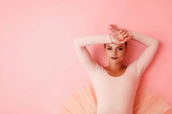 스튜디오 바닥에 분홍색 감각있는 발레리나 분홍색 배경을 배경으로 포즈를 취하고 — 스톡 사진