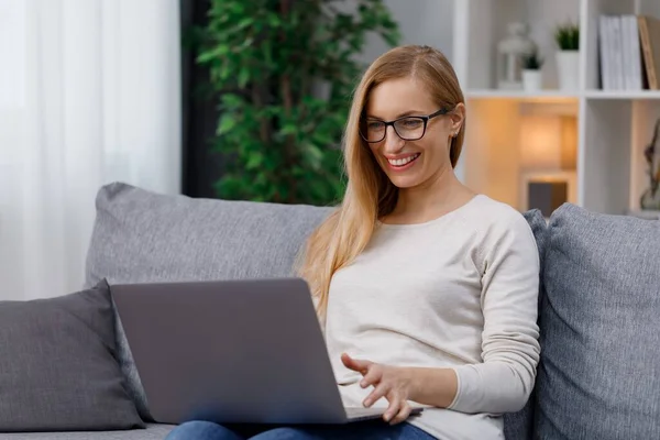 Sıradan Giyinen Mutlu Beyaz Kadın Kanepeye Oturup Bilgisayar Ekranına Bakıyor — Stok fotoğraf