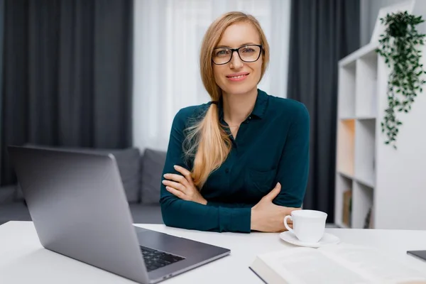 Kulaklıklı Beyaz Kadın Masada Oturuyor Dizüstü Bilgisayarda Çalışıyor Kahve Içiyor — Stok fotoğraf
