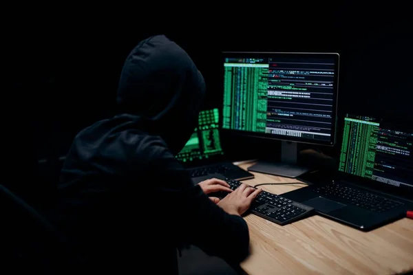 夜の間に大規模なサイバー攻撃を組織化黒パーカーの男性ハッカーのバックビュー プロのプログラマーは デスクに座って現代のコンピュータ上でコーディング — ストック写真