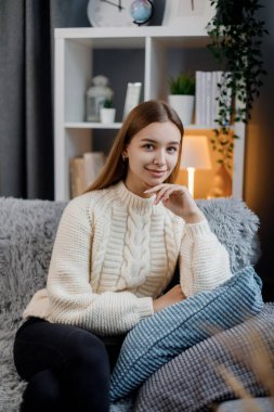 Rahat oturma odasındaki rahat kanepede dinlenen doğal sarı saçlı beyaz bir kadının portresi. Ev hayatı ve boş zaman kavramı.