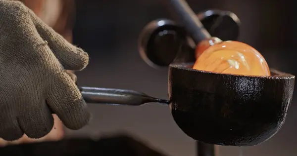 stock image Close-up of an artisan glassblower using gloved hands to form molten glass inside a traditional metal mold, demonstrating precision and skill in a glowing workshop environment.