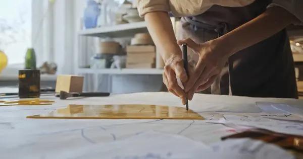 stock image Watch a skilled glass artist precisely cut a yellow glass petal for a decorative floral mirror in her sunlit workshop, highlighting her expertise and the art of glass mosaic crafting.