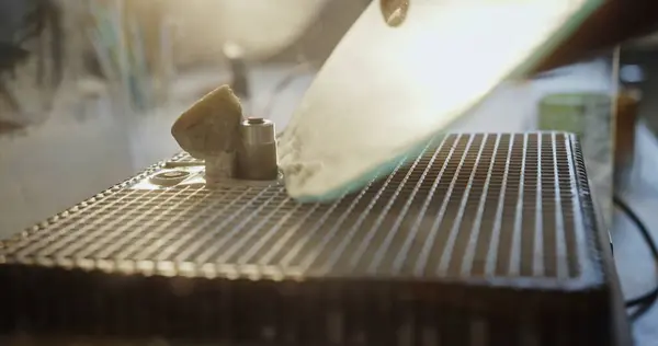 stock image Artistic close-up of a glass edge being ground on a specialized machine in a sunlit artisan workshop, emphasizing the precision and beauty of the glass crafting process.