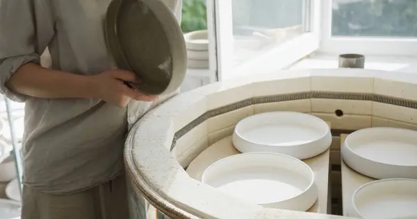 stock image A female clay craftsman carefully places handmade clay bowls into a kiln for baking in her workshop. This process is a crucial step in ceramic creation, highlighting the meticulous attention to detail