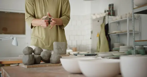 stock image A male potter organizes balls of clay, readying them for shaping on a pottery wheel, in a sunlit workshop filled with finished ceramic bowls.