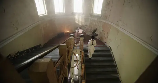 stock image A woman in a white dress ascends the stairs towards a candle-lit table in a castle with an air of mystery.