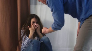 An angry man threatens to beat his wife, and she covers her face with her hands in fear. High quality 4k footage clipart