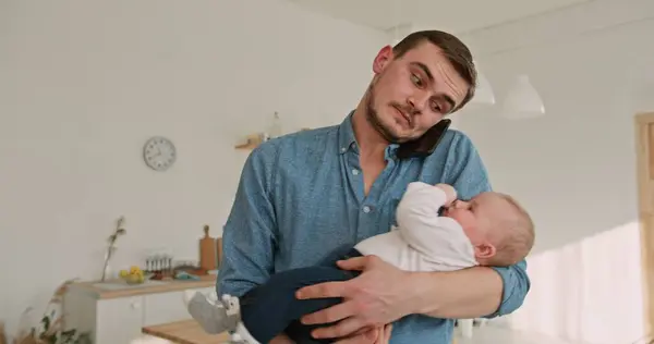 stock image Multitasking Dad Balancing Work Call with Holding Adorable Son at Home. High quality 4k footage