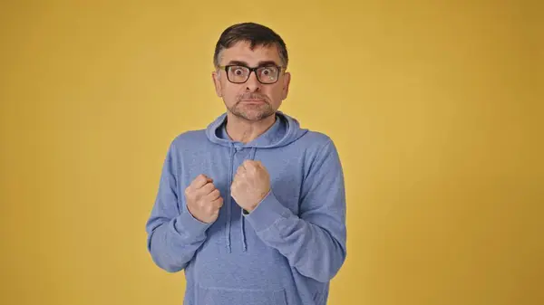 stock image Assertive senior man in glasses making threatening gesture against yellow background. High quality 4k footage