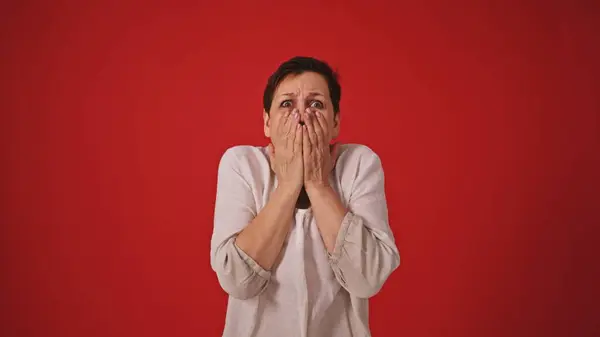 stock image Mature Woman Experiencing Fear and Horror on Red Background. High quality 4k footage