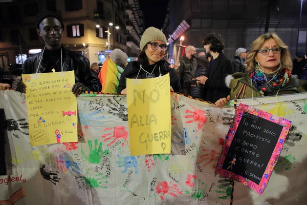 Avellino, İtalya-24 Şubat 2023: Barış bayrakları, protesto işaretleri ve meşaleleri olan insanlar, Ukrayna 'daki savaşın sona ermesini talep etmek üzere düzenlenen bir toplantıya katılıyor ve yürüyüşe katılıyorlar..