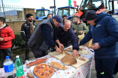 Avellino, İtalya-Şubat 07.2024: Bir grup çiftçi Avrupa Topluluğu 'nun tarım politikalarını protesto ediyor. Traktörleriyle şehrin sokaklarında yürüyorlar. Yerel ürünlerle öğle yemeği yiyorlar..