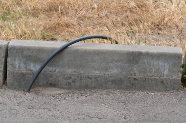 Kalitesiz çalışmanın bir örneği, asfalt yüzeyinde inşaattan sonra bir elektrik kablosu görünür.