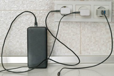 Elektrik kablolarını şarj etmek için üç kablo elektrik prizlerine takılıyor, biri elektrik bankasına yükleniyor.