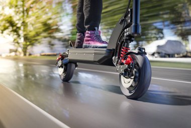 Elektrikli scooter sürüşü şehirde hızlı - ön tekere yakın, hareket bulanıklığı etkisi