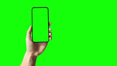 Ofisteki masada boş yeşil ekranlı bir dizüstü bilgisayar, rüzgarda sallanan ağaçlar ve arka planda ofis lambaları olan..