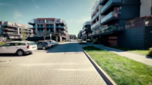 現代の住宅街を通して滑らかなカメラの動き 近くの前景に焦点を当て ぼやけた建物 不動産市場に関するキャプションの背景 — ストック動画