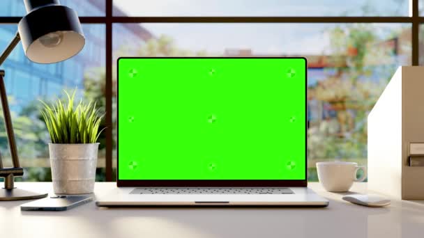 オフィスの机の上に緑の画面が空のノートパソコン風に揺れる木々や背景のオフィスの芽 — ストック動画