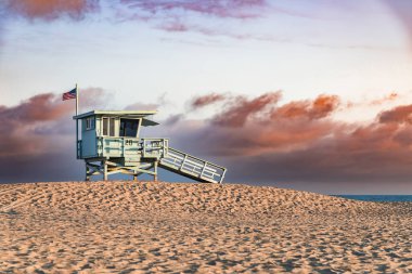 Santa Monica, California sahilindeki cankurtaran kulesi dramatik bulutlarla dolu güzel bir günbatımında.