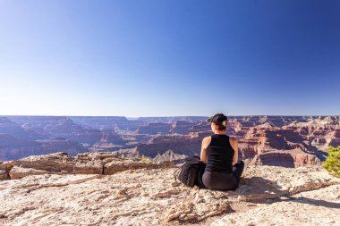 Kız, Amerika 'daki Büyük Kanyon' a bakan bir kayanın kenarında rahatlar ve manzaraya hayran kalır..