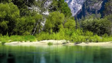 Yosemite Ulusal Parkı 'ndaki Merced Nehri. Nehrin yüzeyine yansıyan dağların güzel manzarası. Pürüzsüz Camra geçişi.