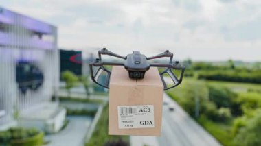 Modern binaların arka planında tasvir edilen paketi şehre teslim eden bir insansız hava aracı. Modern bir şehir ortamında gelecekteki dağıtım teknolojisinin, insansız hava araçlarının ve lojistiğin mükemmel bir temsili..
