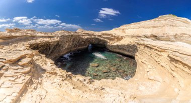 Korsika 'daki doğal Grotte de Saint-Antoine mağarasının nefes kesici manzarası. Altın kaya oluşumları kristal berrak su ve parlak mavi gökyüzü ile tezat oluşturur..