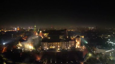 Yeni yıl arifesinde Krakow 'daki Kraliyet Wawel Kalesi' nin çarpıcı havai fişeklerle aydınlatılmış muhteşem hava manzarası. Kültür, tarih ve olaylarla ilgili materyaller için mükemmel bir geçmiş. Yumuşak bir yörüngeyle kamerayı geri çek
