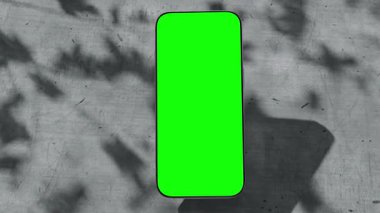 Yeşil ekran pürüzsüz dönüşlü akıllı telefon, beton zemin üzerine kurulmuş üç sahne. İzleme videosu ve luima matte dahil