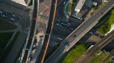 Çeşitli yönlerde ilerleyen çoklu yükseltilmiş yol ve araçlarla dolu işlek bir şehir kavşağının yukarıdan aşağıya görüntüsü.