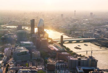 Günbatımında Londra ve Thames nehri arasında Londra şehri ve gökdelenleri olan bankacılık bölgesi yer almaktadır.