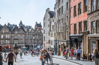 İskoçya, Edinburg - 24 Ağustos 2022: Victoria sokağı güzel bir kavis ve renkli dükkan cepheleriyle 1860 'da inşa edilmiş ve modaya uygun İskoç Baronluk tarzında tasarlanmıştır. İnsanlar yolda yürüyor.