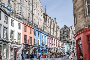 İskoçya, Edinburg - 24 Ağustos 2022: Victoria sokağı güzel bir kavis ve renkli dükkan cepheleriyle 1860 'da inşa edilmiş ve modaya uygun İskoç Baronluk tarzında tasarlanmıştır. İnsanlar yolda yürüyor.