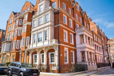 Londra, İngiltere - 9 Eylül 2023: Mayfair 'deki güzel periyodik binalar ve yolda park edilmiş lüks arabalar. Mayfair, lüks bir yaşam tarzıyla yaşamak için en zengin yerlerden biri.