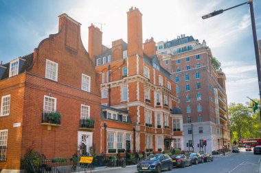 Londra, İngiltere - 9 Eylül 2023: Mayfair 'deki güzel periyodik binalar ve yolda park edilmiş lüks arabalar. Mayfair, lüks bir yaşam tarzıyla yaşamak için en zengin yerlerden biri.