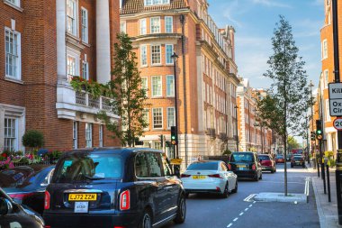 Londra, İngiltere - 9 Eylül 2023: Mayfair 'deki güzel periyodik binalar ve yolda park edilmiş lüks arabalar. Mayfair, lüks bir yaşam tarzıyla yaşamak için en zengin yerlerden biri.