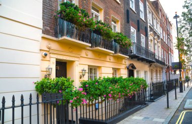Londra, İngiltere - 9 Eylül 2023: Mayfair 'deki güzel periyodik binalar ve yolda park edilmiş lüks arabalar. Mayfair, lüks bir yaşam tarzıyla yaşamak için en zengin yerlerden biri.
