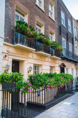 Londra, İngiltere - 9 Eylül 2023: Mayfair 'deki güzel periyodik binalar ve yolda park edilmiş lüks arabalar. Mayfair, lüks bir yaşam tarzıyla yaşamak için en zengin yerlerden biri.