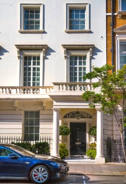 Londra, İngiltere - 9 Eylül 2023: Mayfair 'deki güzel periyodik binalar ve yolda park edilmiş lüks arabalar. Mayfair, lüks bir yaşam tarzıyla yaşamak için en zengin yerlerden biri.