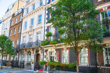 Londra, İngiltere - 9 Eylül 2023: Mayfair 'deki güzel periyodik binalar ve yolda park edilmiş lüks arabalar. Mayfair, lüks bir yaşam tarzıyla yaşamak için en zengin yerlerden biri.