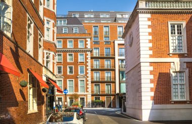Londra, İngiltere - 9 Eylül 2023: Mayfair 'deki güzel periyodik binalar ve yolda park edilmiş lüks arabalar. Mayfair, lüks bir yaşam tarzıyla yaşamak için en zengin yerlerden biri.