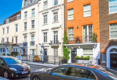 Londra, İngiltere - 9 Eylül 2023: Mayfair 'deki güzel periyodik binalar ve yolda park edilmiş lüks arabalar. Mayfair, lüks bir yaşam tarzıyla yaşamak için en zengin yerlerden biri.