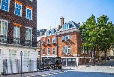 Londra, İngiltere - 9 Eylül 2023: Mayfair 'deki güzel periyodik binalar ve yolda park edilmiş lüks arabalar. Mayfair, lüks bir yaşam tarzıyla yaşamak için en zengin yerlerden biri.