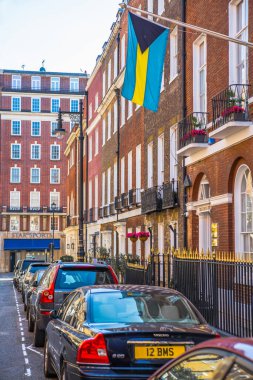 Londra, İngiltere - 9 Eylül 2023: Mayfair 'deki güzel periyodik binalar ve yolda park edilmiş lüks arabalar. Mayfair, lüks bir yaşam tarzıyla yaşamak için en zengin yerlerden biri.