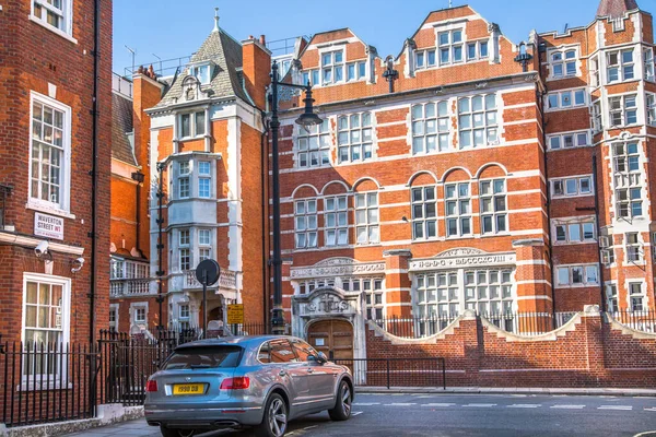 Londra, İngiltere - 9 Eylül 2023: Mayfair 'deki güzel periyodik binalar ve yolda park edilmiş lüks arabalar. Mayfair, lüks bir yaşam tarzıyla yaşamak için en zengin yerlerden biri.