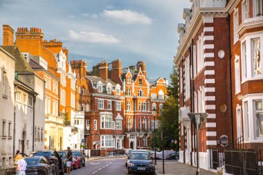Londra, İngiltere - 9 Eylül 2023: Periyodik binaları ve caddeye park edilmiş lüks arabaları olan güzel Kensington caddeleri. Kensington lüks bir yaşam tarzıyla yaşamak için en zengin yerlerden biri.
