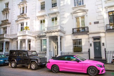 Londra, İngiltere - 9 Eylül 2023: Periyodik binaları ve caddeye park edilmiş lüks arabaları olan güzel Kensington caddeleri. Kensington lüks bir yaşam tarzıyla yaşamak için en zengin yerlerden biri.