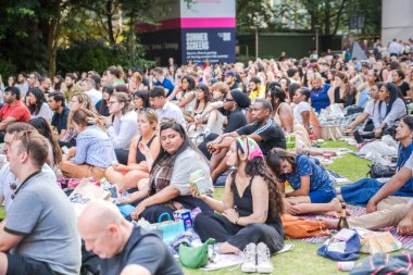 Londra, İngiltere - 30 Temmuz 2024: Bir sürü insanla Kanada meydanı, ofis çalışanları iş gününden sonra halka açık etkinliğin tadını çıkarıyorlar. İnsanlar kanarya iskelesinde film izler, içki içer ve piknik yapar.