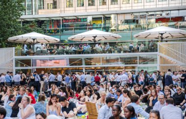 Londra, İngiltere - 30 Temmuz 2024: Bir sürü insanla Kanada meydanı, ofis çalışanları iş gününden sonra halka açık etkinliğin tadını çıkarıyorlar. İnsanlar kanarya iskelesinde film izler, içki içer ve piknik yapar.